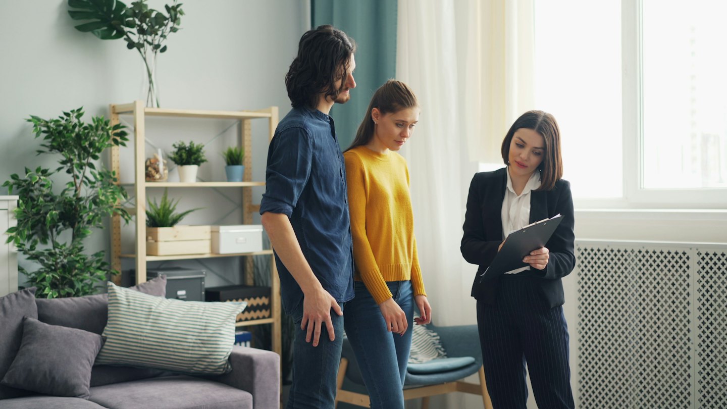 Un agente immobiliare mostra un soggiorno moderno a una coppia.