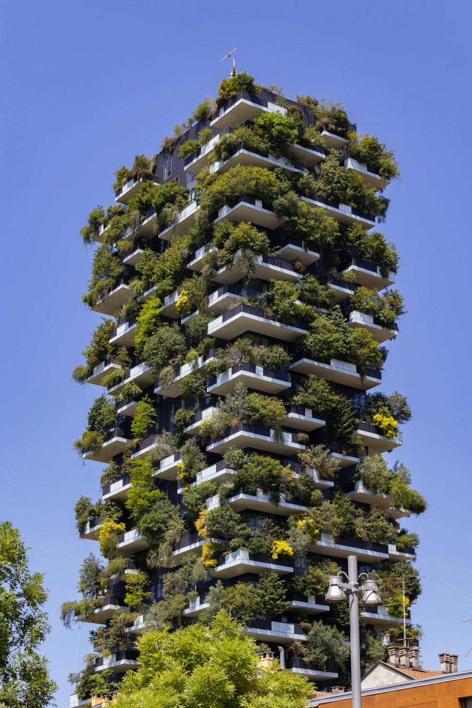 Moderno edificio residenziale con balconi ricoperti di lussureggianti piante verdi.
